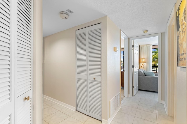 hallway featuring a textured ceiling and light tile patterned floors