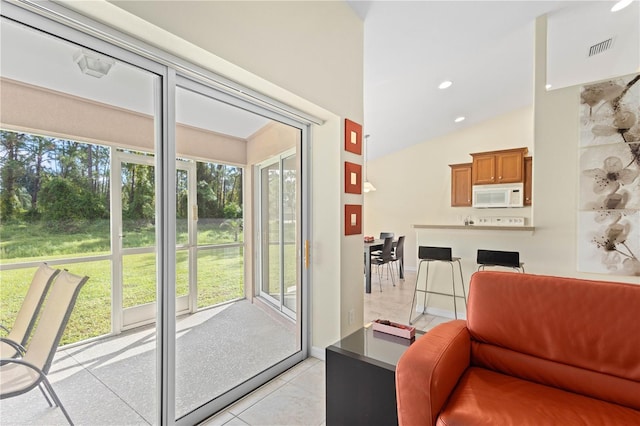 doorway with light tile patterned flooring, a wealth of natural light, and vaulted ceiling