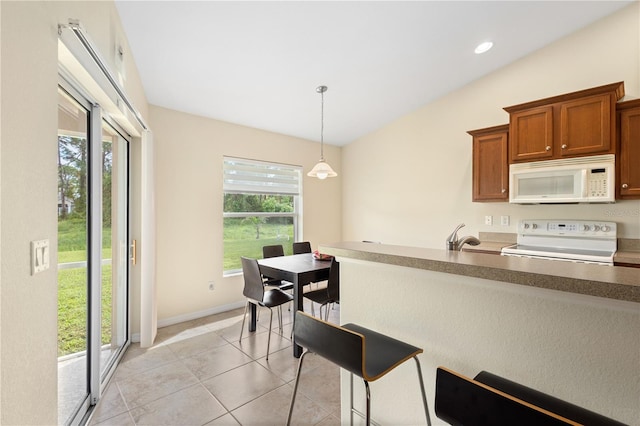 kitchen with white appliances, sink, vaulted ceiling, decorative light fixtures, and light tile patterned floors