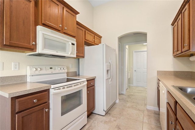 kitchen featuring white appliances, sink, and light tile patterned floors