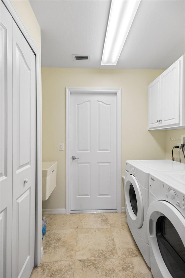 laundry room featuring washing machine and dryer and cabinets