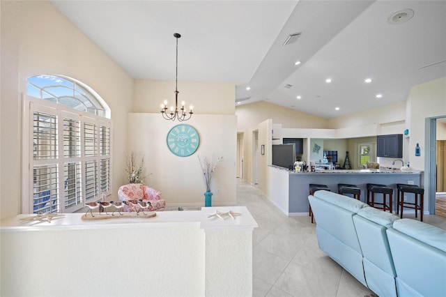 interior space featuring kitchen peninsula, decorative light fixtures, stainless steel refrigerator, an inviting chandelier, and a kitchen bar