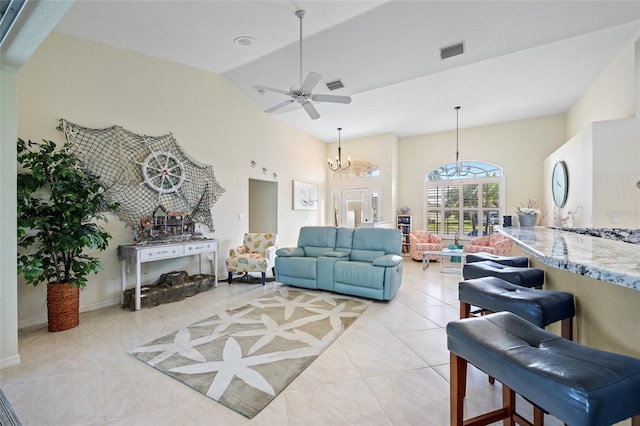 tiled living room with ceiling fan with notable chandelier and high vaulted ceiling