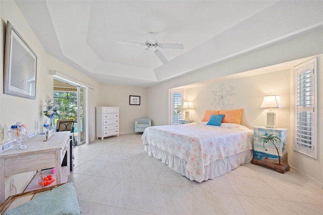 bedroom featuring ceiling fan, light tile patterned flooring, and a tray ceiling