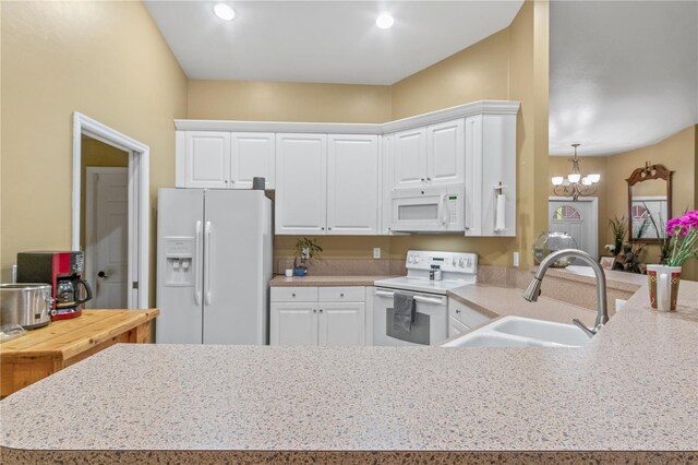 kitchen with kitchen peninsula, an inviting chandelier, white cabinetry, sink, and white appliances