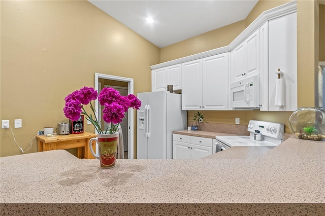 kitchen featuring white cabinets, vaulted ceiling, and white appliances