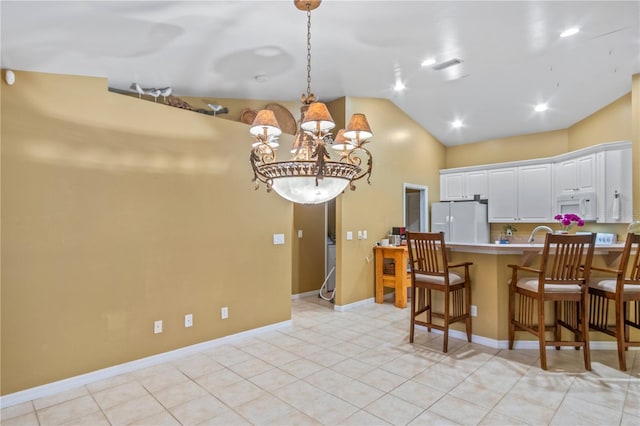 kitchen featuring white appliances, a kitchen breakfast bar, lofted ceiling, white cabinets, and an inviting chandelier