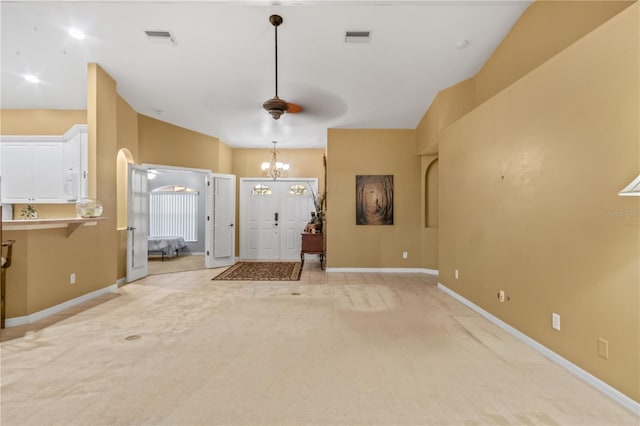 entryway featuring ceiling fan with notable chandelier, vaulted ceiling, and light colored carpet