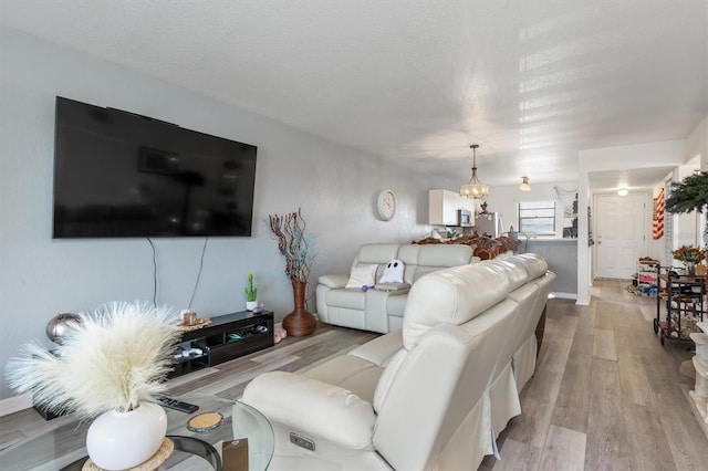 living room featuring a textured ceiling, light wood-type flooring, and a chandelier