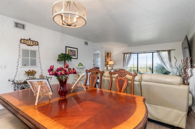 dining room featuring a textured ceiling, light hardwood / wood-style floors, and a chandelier