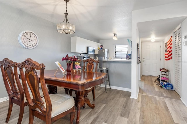 dining room featuring light wood-type flooring and a chandelier