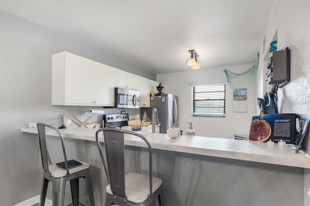 kitchen featuring a breakfast bar, white cabinets, and appliances with stainless steel finishes