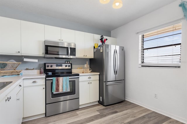 kitchen featuring light hardwood / wood-style flooring, stainless steel appliances, and white cabinetry