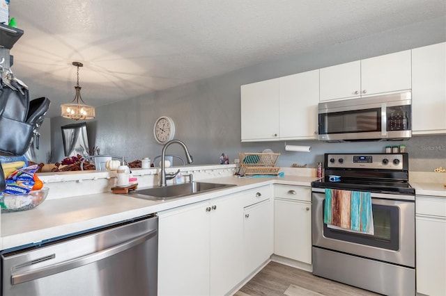 kitchen featuring pendant lighting, white cabinetry, appliances with stainless steel finishes, and sink