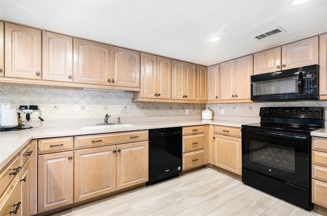 kitchen with black appliances, light hardwood / wood-style floors, decorative backsplash, and sink