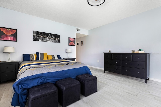 bedroom featuring light hardwood / wood-style flooring and a textured ceiling