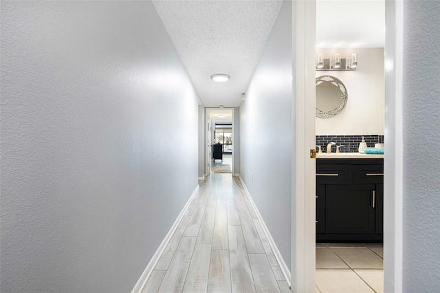 hallway with light wood-type flooring and a textured ceiling