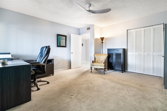 carpeted home office featuring a textured ceiling and ceiling fan