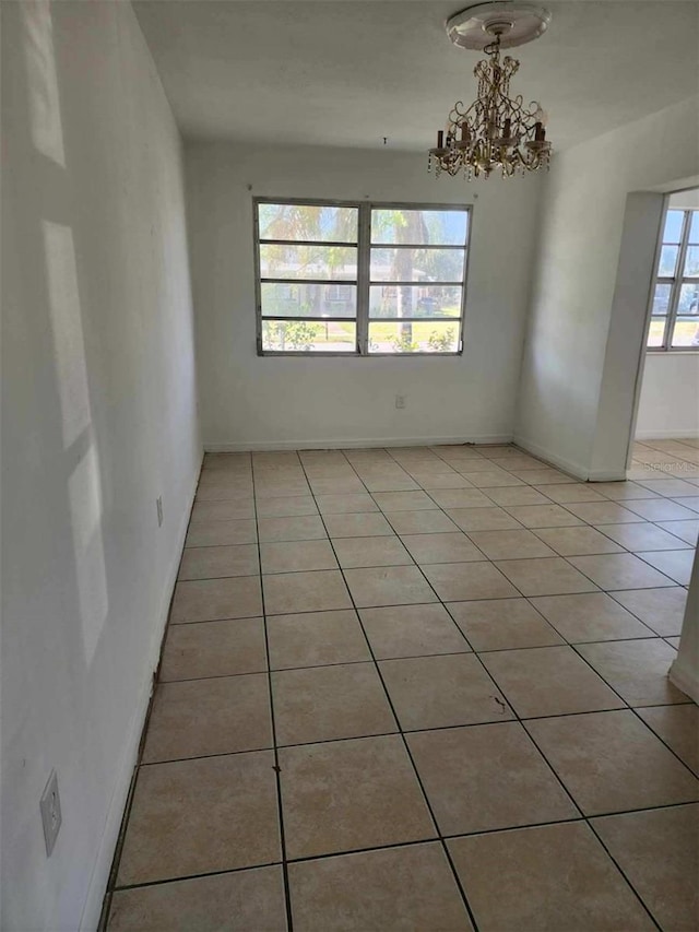 spare room with light tile patterned floors and a notable chandelier