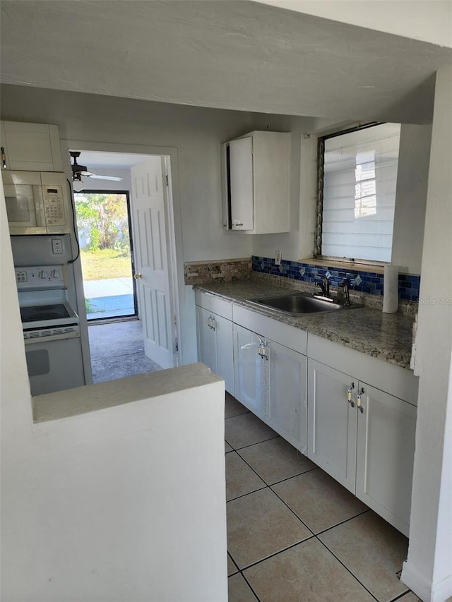 kitchen with white appliances, light tile patterned floors, sink, and white cabinets