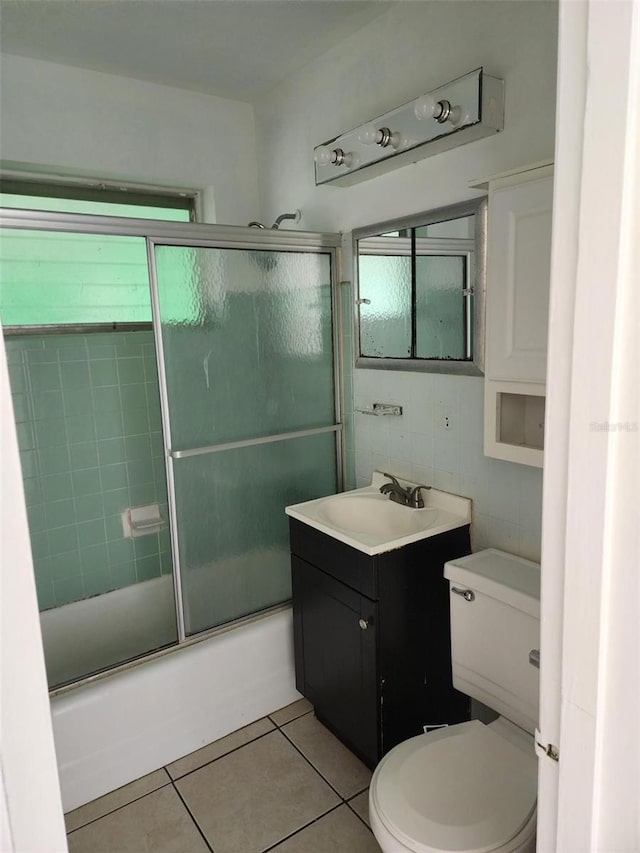 full bathroom with toilet, shower / bath combination with glass door, tile walls, vanity, and tile patterned flooring