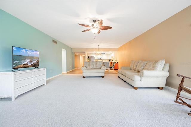 carpeted living room featuring ceiling fan with notable chandelier