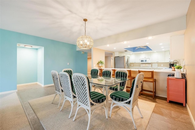 dining space with ceiling fan with notable chandelier and sink