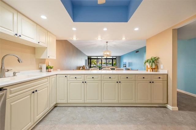 kitchen with a notable chandelier, kitchen peninsula, pendant lighting, and sink