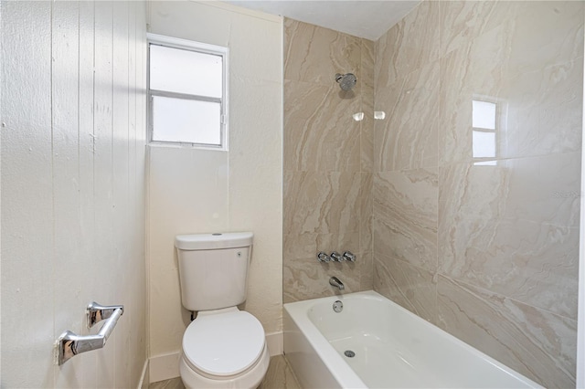 bathroom featuring tiled shower / bath combo and toilet