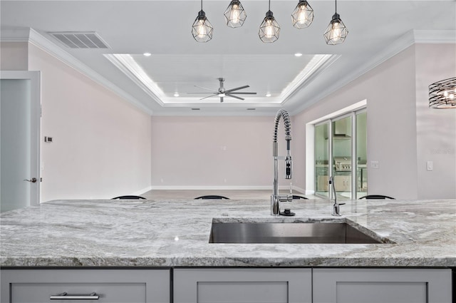 kitchen featuring gray cabinets, sink, light stone counters, and crown molding