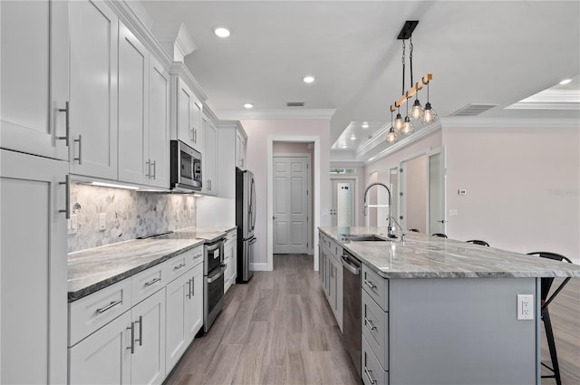 kitchen featuring appliances with stainless steel finishes, white cabinets, a spacious island, and sink