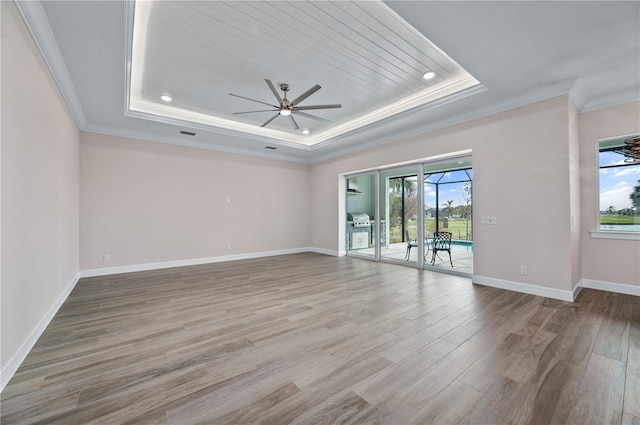 spare room with ornamental molding, ceiling fan, light wood-type flooring, and a raised ceiling