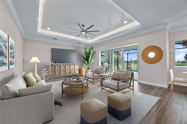 living room with hardwood / wood-style flooring, a tray ceiling, plenty of natural light, and ceiling fan