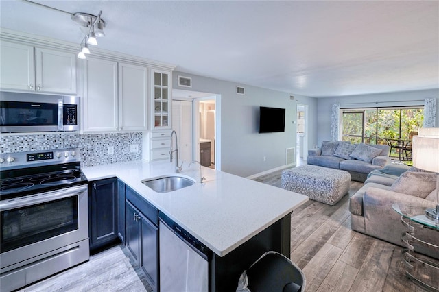 kitchen with light wood-type flooring, stainless steel appliances, sink, kitchen peninsula, and white cabinetry