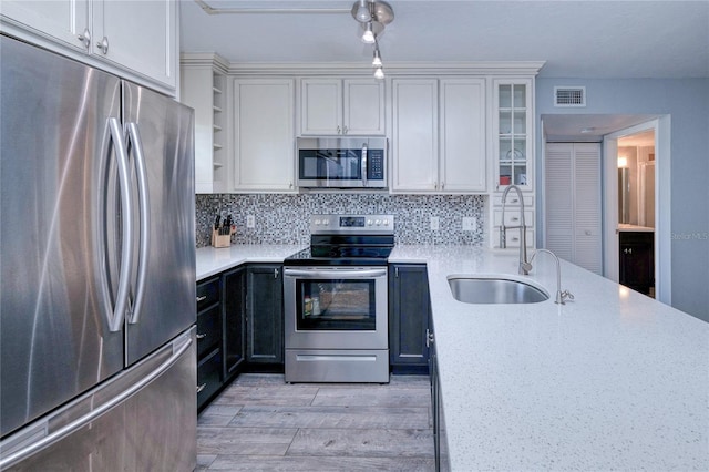 kitchen featuring light stone countertops, white cabinetry, sink, and stainless steel appliances