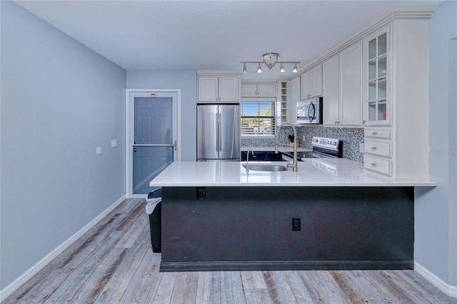 kitchen featuring light hardwood / wood-style floors, sink, stainless steel appliances, kitchen peninsula, and white cabinets