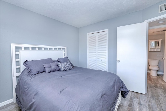 bedroom with hardwood / wood-style flooring, connected bathroom, a closet, and a textured ceiling