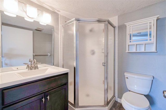 bathroom with vanity, walk in shower, toilet, and a textured ceiling