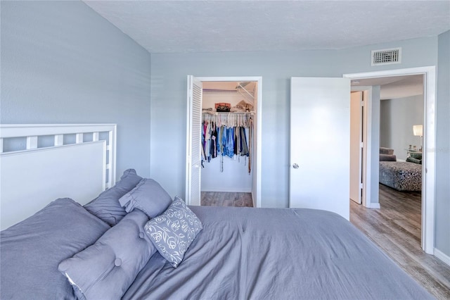 bedroom with light wood-style floors, visible vents, a walk in closet, and a closet