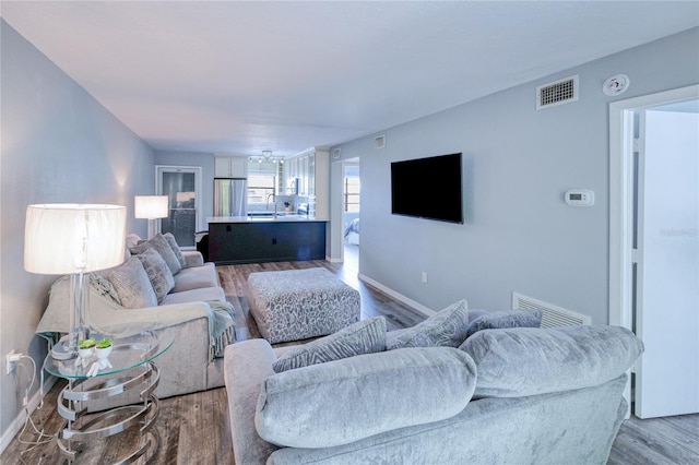 living room with visible vents, baseboards, and wood finished floors