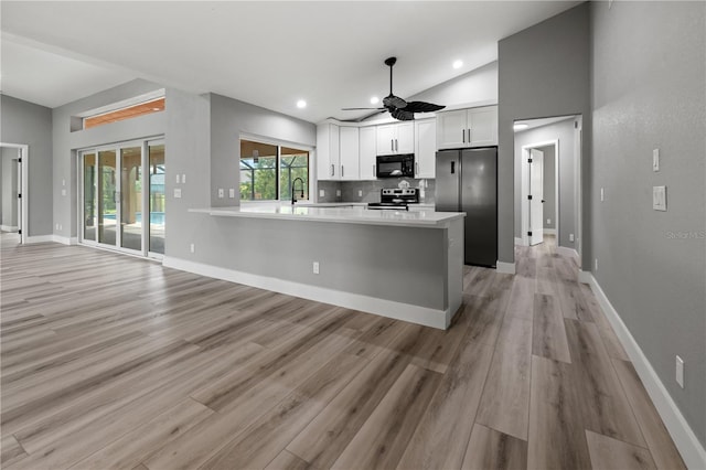 kitchen with white cabinetry, stainless steel appliances, tasteful backsplash, kitchen peninsula, and vaulted ceiling