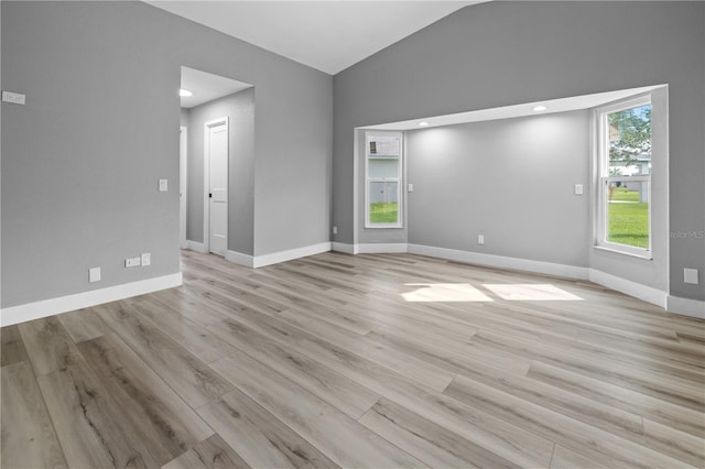 empty room with light hardwood / wood-style floors and vaulted ceiling