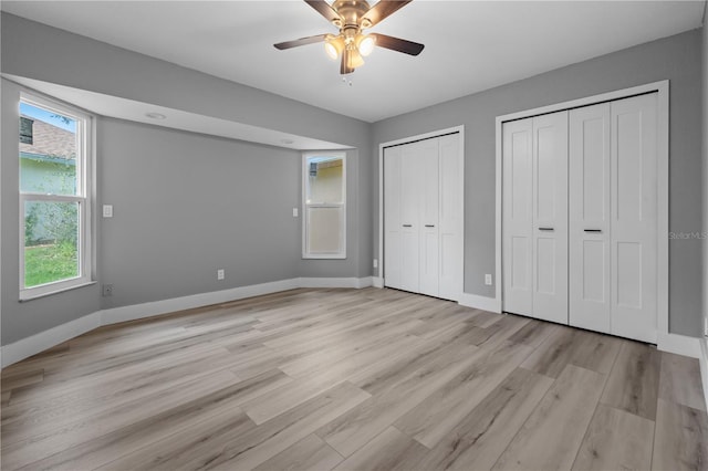 unfurnished bedroom featuring multiple closets, ceiling fan, and light hardwood / wood-style flooring