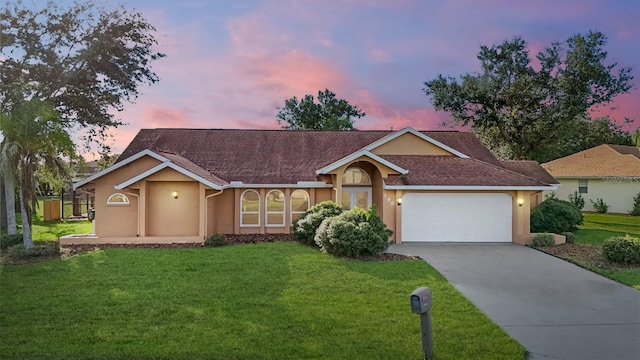 ranch-style house featuring stucco siding, driveway, an attached garage, and a front lawn