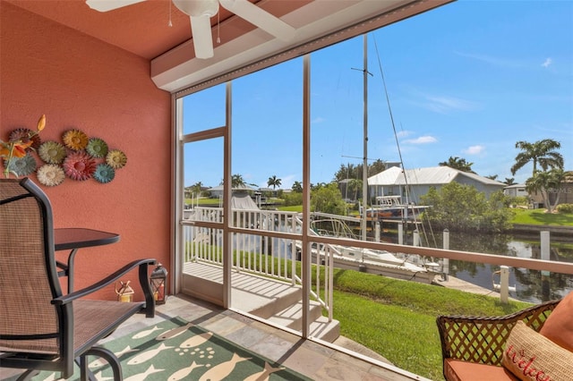 sunroom featuring ceiling fan and a water view