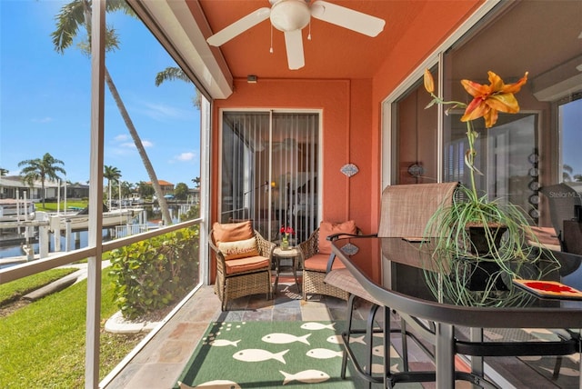 sunroom featuring a water view and ceiling fan