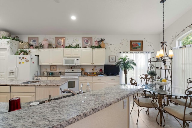 kitchen featuring light stone counters, sink, white appliances, decorative light fixtures, and a chandelier