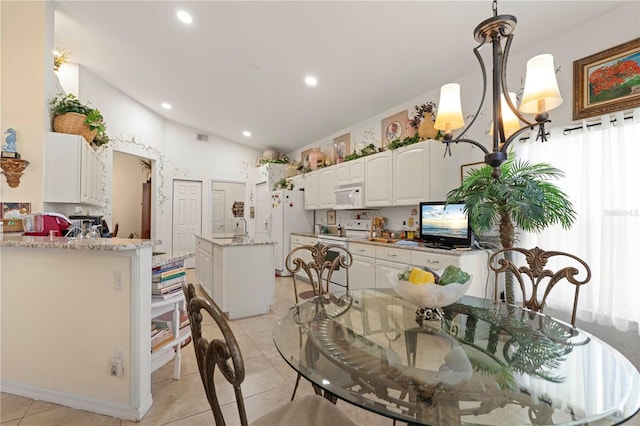 kitchen with lofted ceiling, white cabinetry, white appliances, light tile patterned floors, and decorative light fixtures