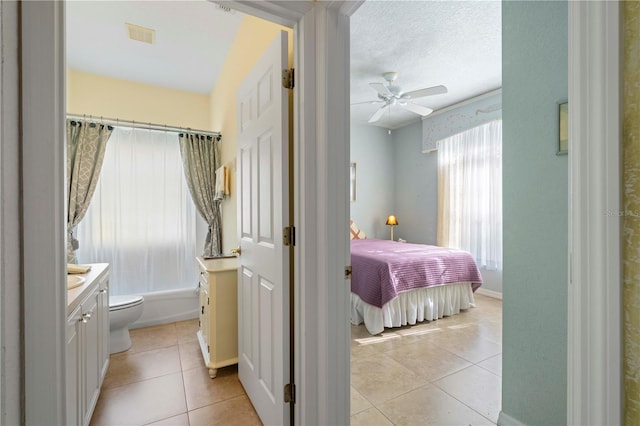 bedroom with ceiling fan, light tile patterned floors, and a textured ceiling