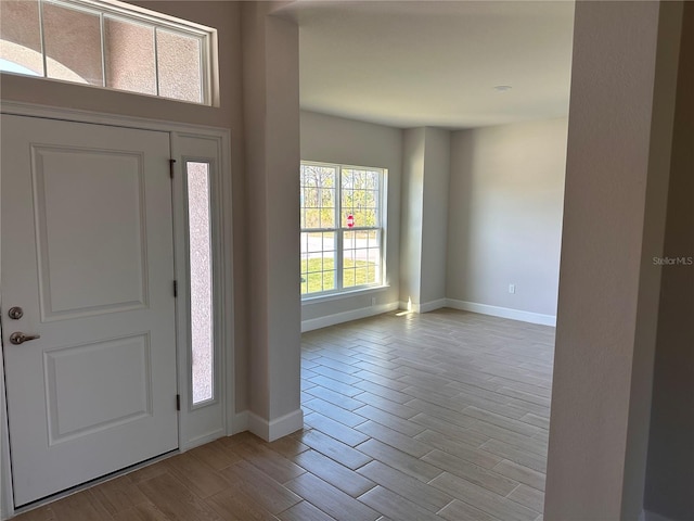 foyer entrance with light wood-style flooring and baseboards